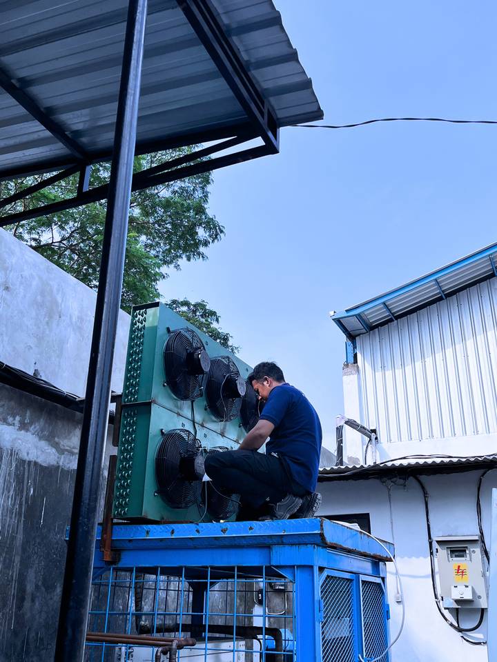 Teknisi memasang unit kondensor cold storage